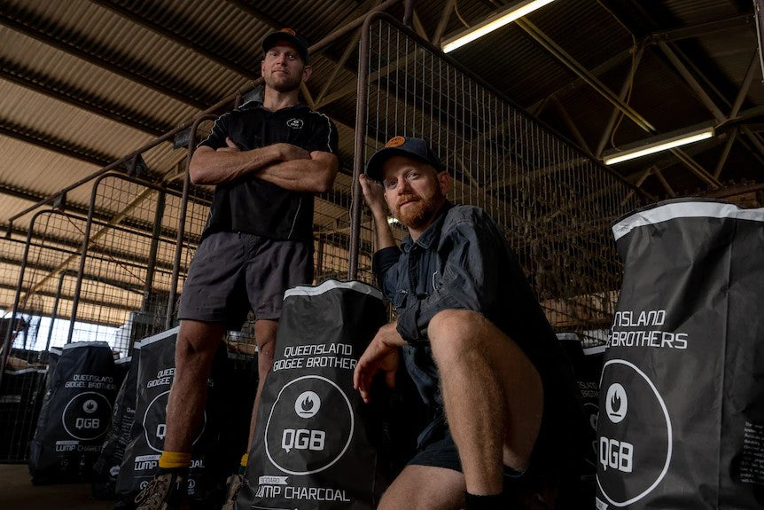 Queensland Gidgee Brothers Kneeling In Front Of Bags Of Their Charcoal